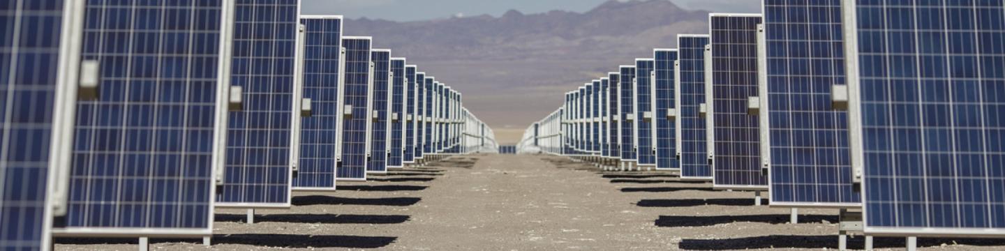 Rows of solar panels installed in a desert landscape with mountains in the background, illustrating renewable energy development in Mexico.