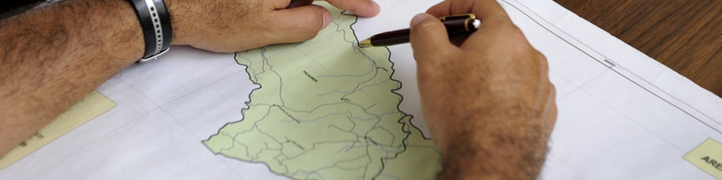 Unas manos marcan un punto sobre un mapa.