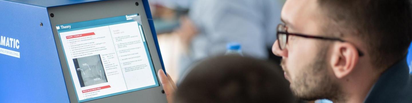 Zwei Auszubildende schauen auf den Bildschirm einer Maschine.