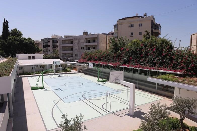 Ein Schulhof mit einem neugebauten, modernen Fußball- und Basketballplatz in der Mitte.