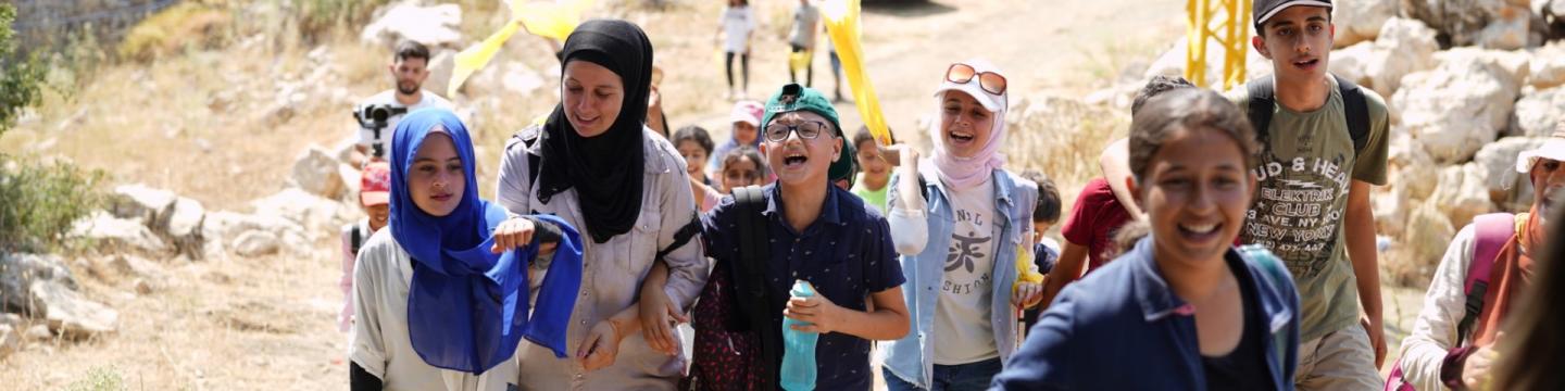 Eine Gruppe von Jugendlichen läuft mit Betreuer*innen einen Hügel hinauf. Copyright: GIZ/MSWR Production