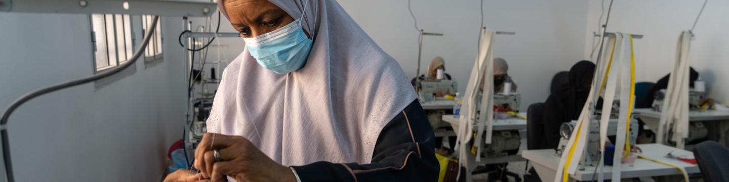 Bei einem Nähtraining arbeitet eine Frau an einer Nähmaschine.