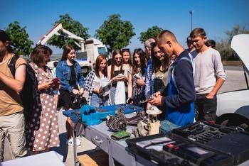 Ein Mechniker erklärt jungen Menschen sein Werkzeug.