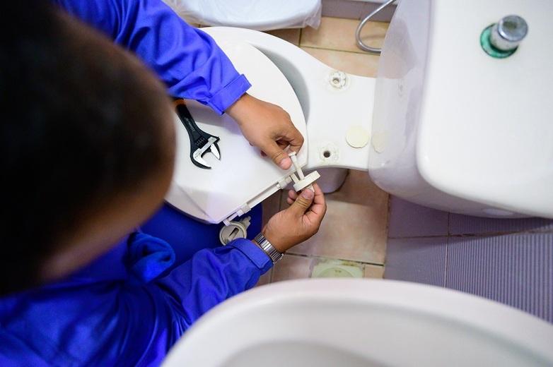 A participant in a technical training course for basic sanitation skills repairs a toilet seat in an orphanage in Jordan