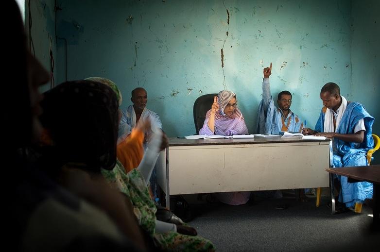 Mehrere Personen sitzen in einem Raum und heben teilweise die Hände zur Abstimmung. Copyright: GIZ