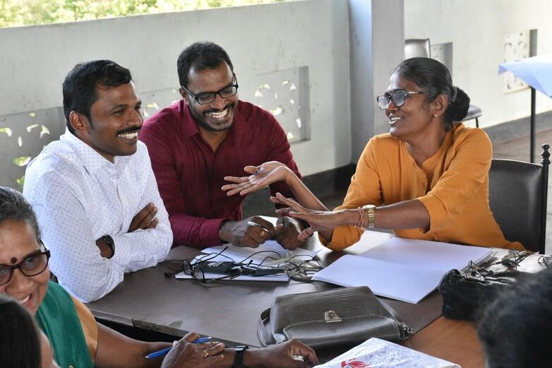Geschichtslehrer*innen sitzen bei einem Workshop an einem Tisch zusammen und unterhalten sich.