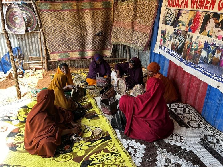 Seven women weave baskets, bags and carpets that will later be sold.