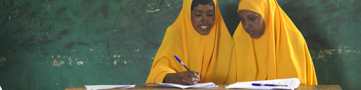 Zwei Mädchen sitzen zusammen und bearbeiten Schulungsunterlagen.