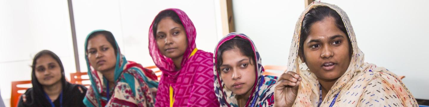 Eine Gruppe verschleierter Frauen und Mädchen sitzt an einem großen Glastisch.