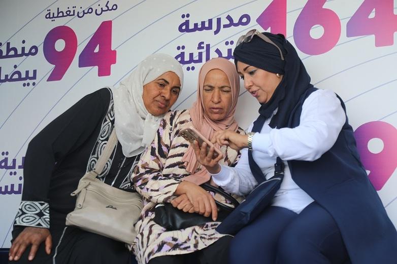 Three women look at a smartphone.