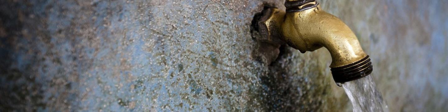 Aus einem Wandwasserhahn kommt Wasser.