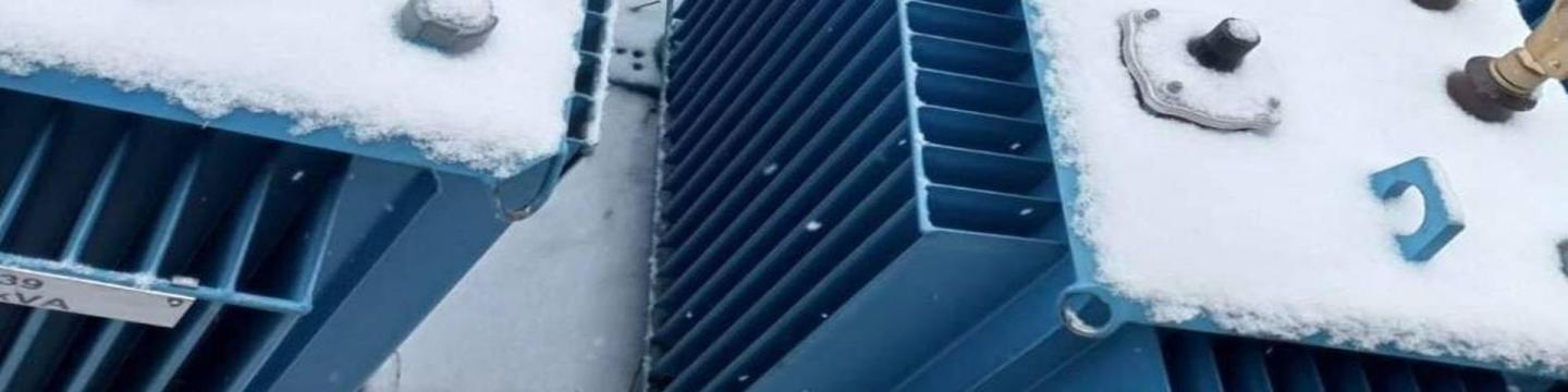 Системи зберігання енергії в засніжених синіх контейнерах, що стоять пліч-о-пліч.