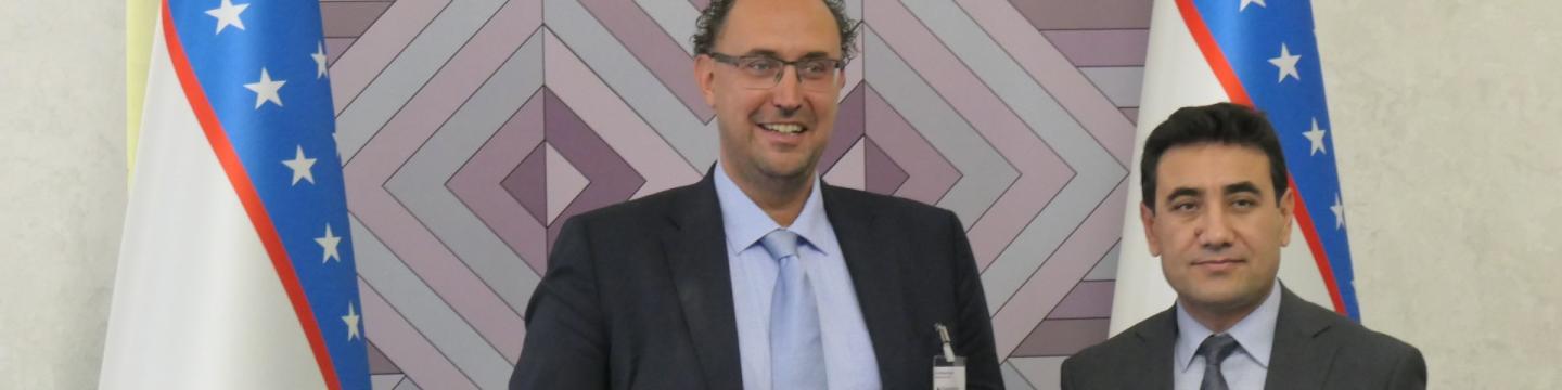 Andreas Kerst und Amalkhon Ortikov stehen vor usbekischen Flaggen.