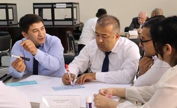 Verschiedene Gruppen von Personen sitzen gemeinsam an Tischen, diskutieren und notieren Ideen.