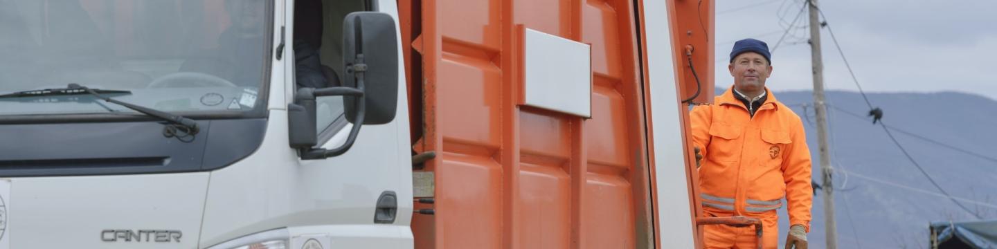 Ein Mitarbeiter der Müllentsorgung hinter einem Fahrzeug der Müllabfuhr.