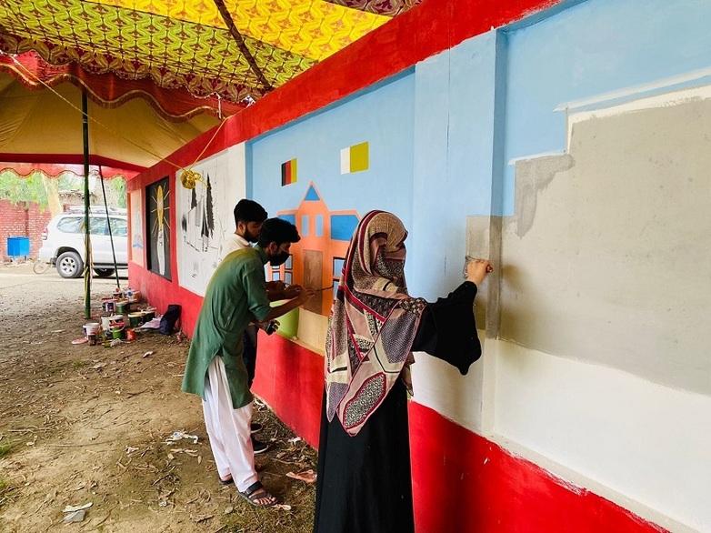 Three young people painting a wall with murals. Copyright: GIZ