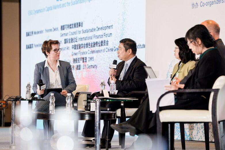 Deutsche und chinesische Vertreter*innen sprechen auf einer Bühne bei einem Gipfeltreffen.