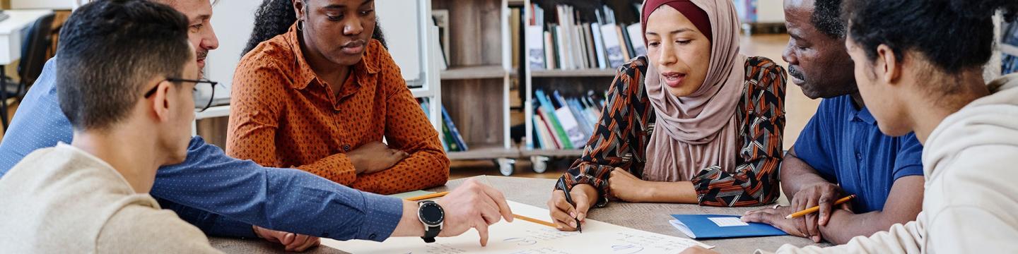 Menschen verschiedener Nationalitäten besprechen sich an einem Tisch