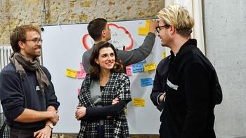 Bei einem Workshop stehen vier junge Menschen zusammen und unterhalten sich.