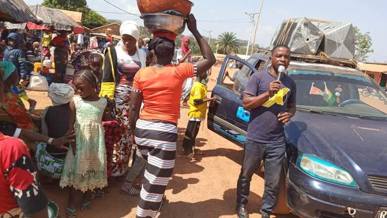 Ein Mann mit Mikrofon klärt auf einem Markt über die COVID-19-Impfung auf.