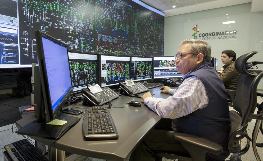 Two people monitoring power supplies using several computers.