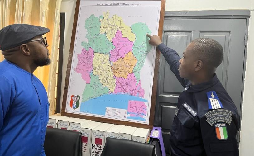 Deux personnes examinant une carte de la Côte d’Ivoire, l’une d’elles, en uniforme des commandos de la gendarmerie, montre un endroit à la frontière avec le Ghana et le Burkina Faso.