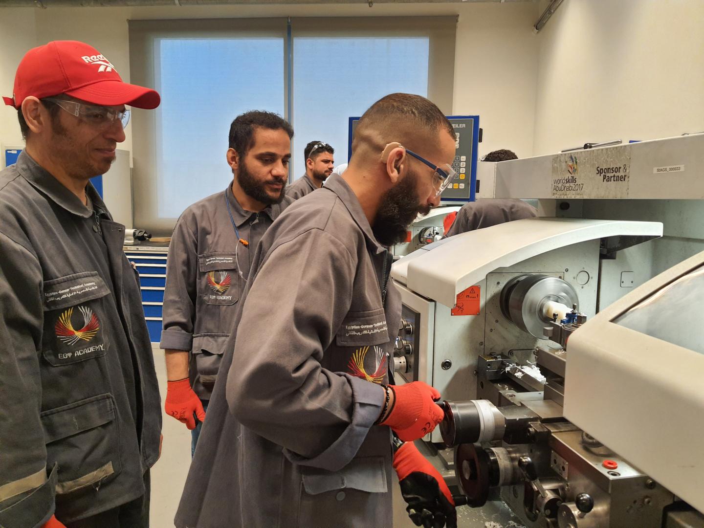 Männer in einer Werkstatt arbeiten an einer Maschine.