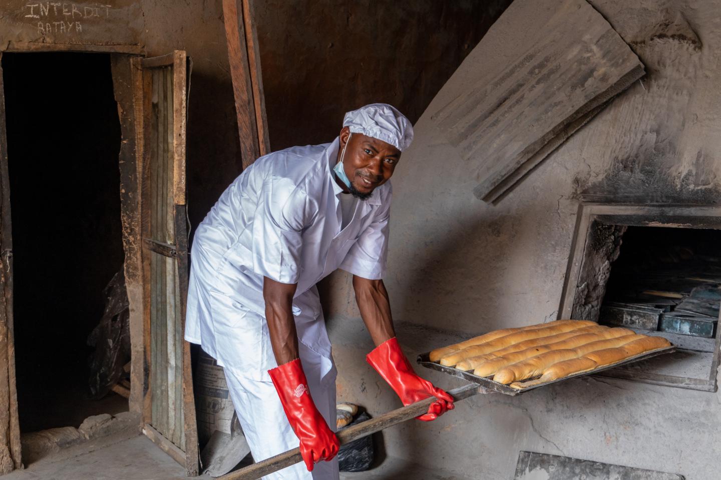 A baker slides bread into an oven.