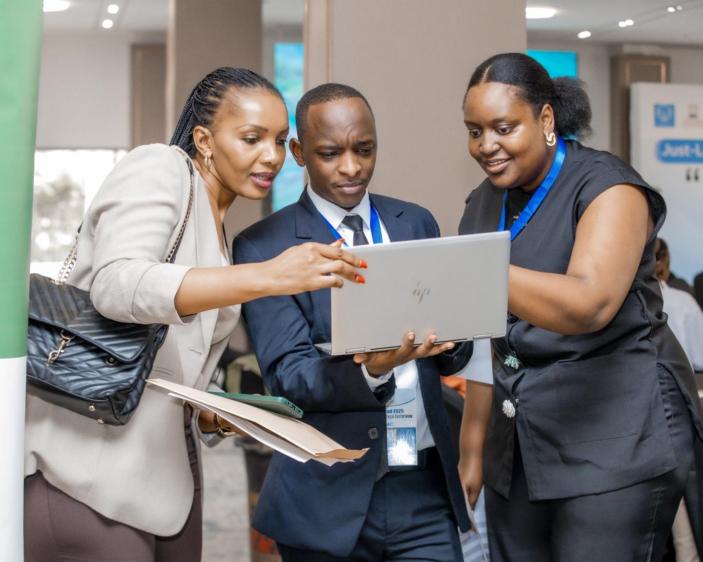 Drei Personen im Arbeitskontext schauen auf einen Laptop.