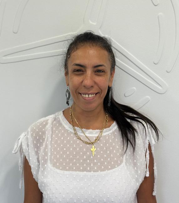 Hanna Reem steht vor einer weißen Wand und lächelt