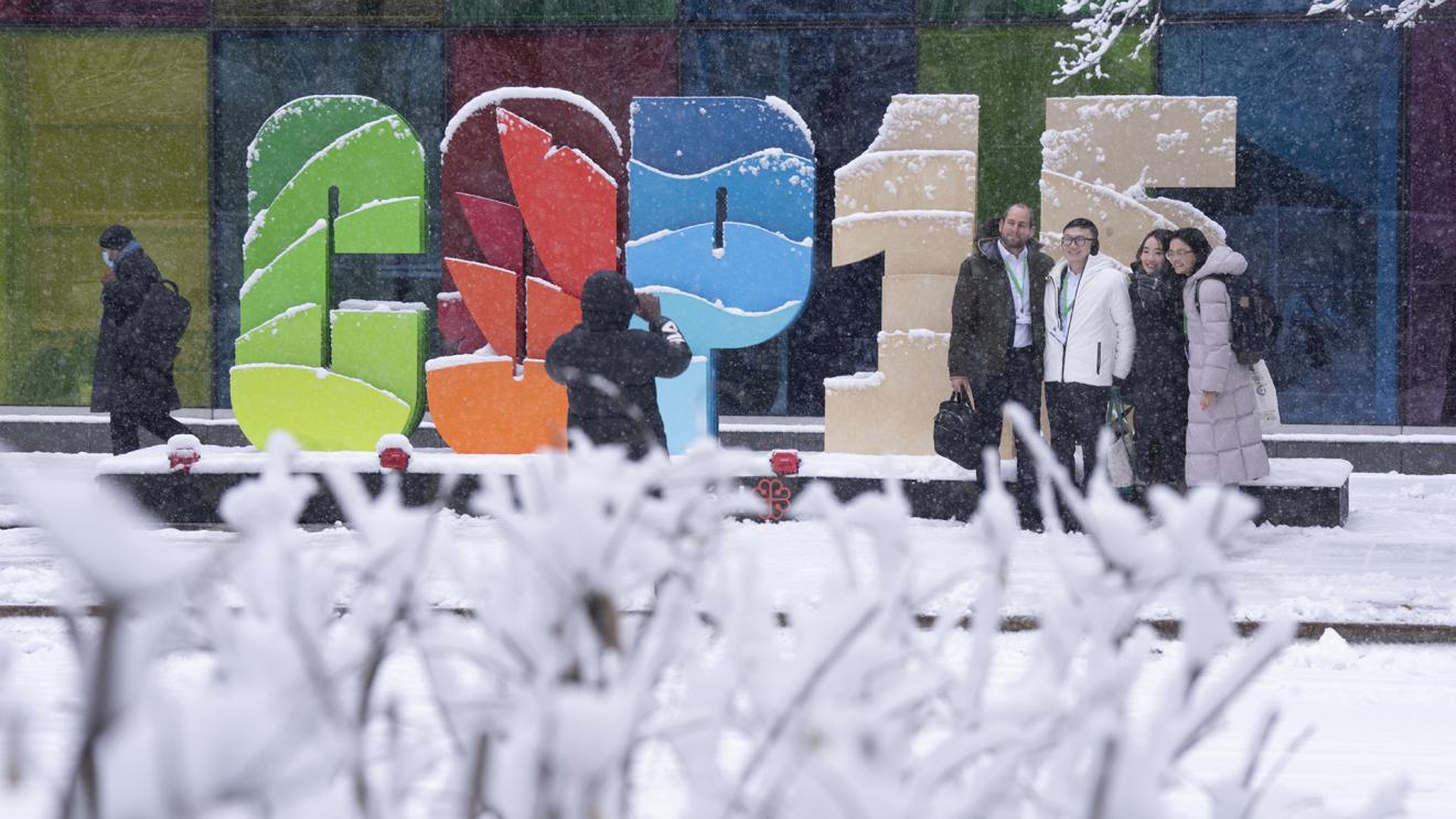 A group of people are photographed in front of a COP15 display.