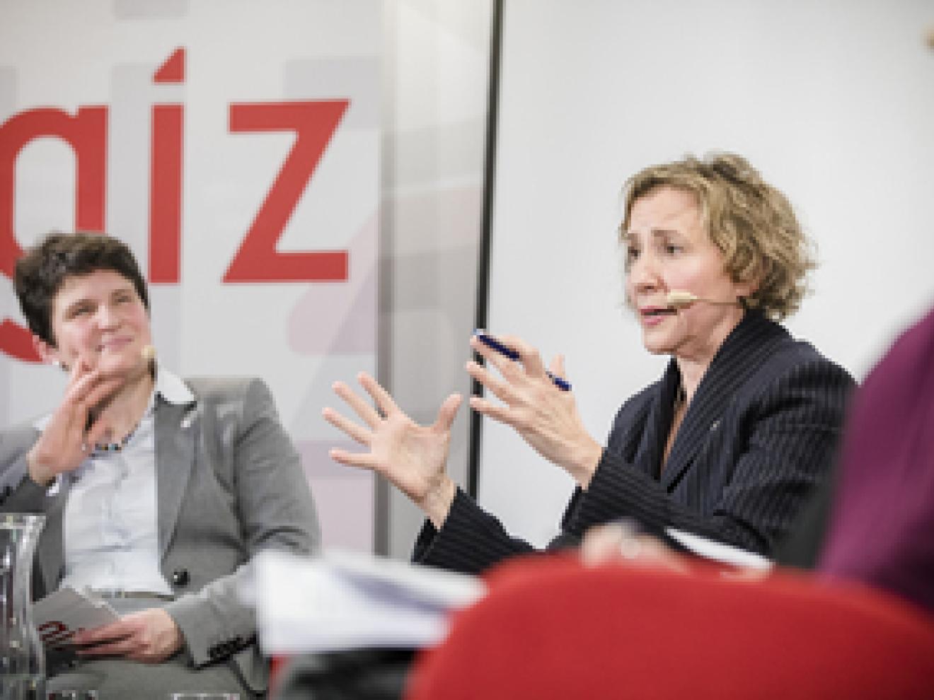 Zwei Frauen sitzen auf Stühlen nebeneinander