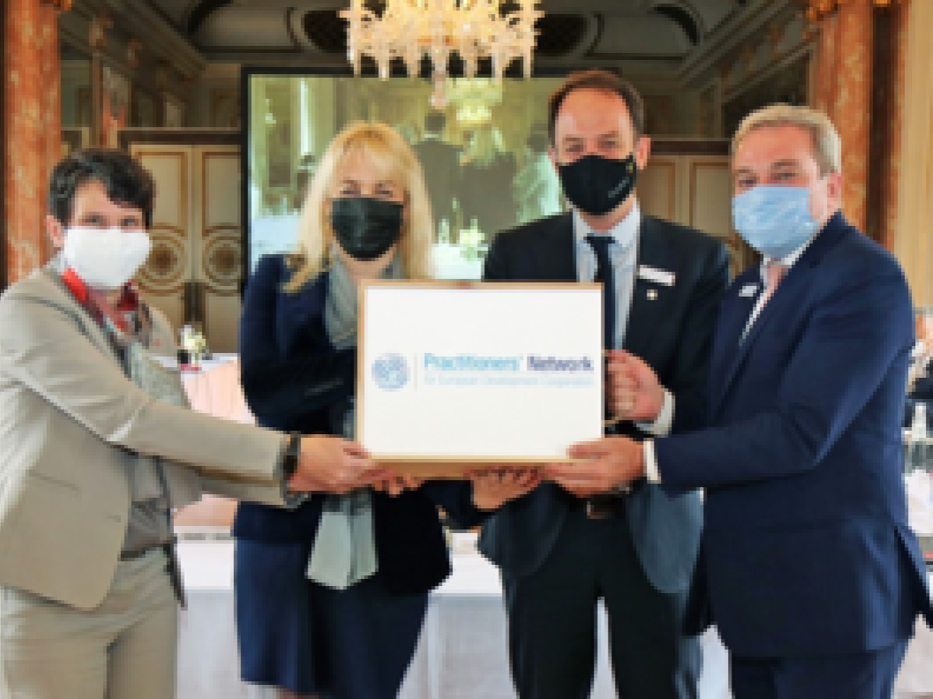 Vier Personen mit Gesichtsmasken halten ein Schild hoch