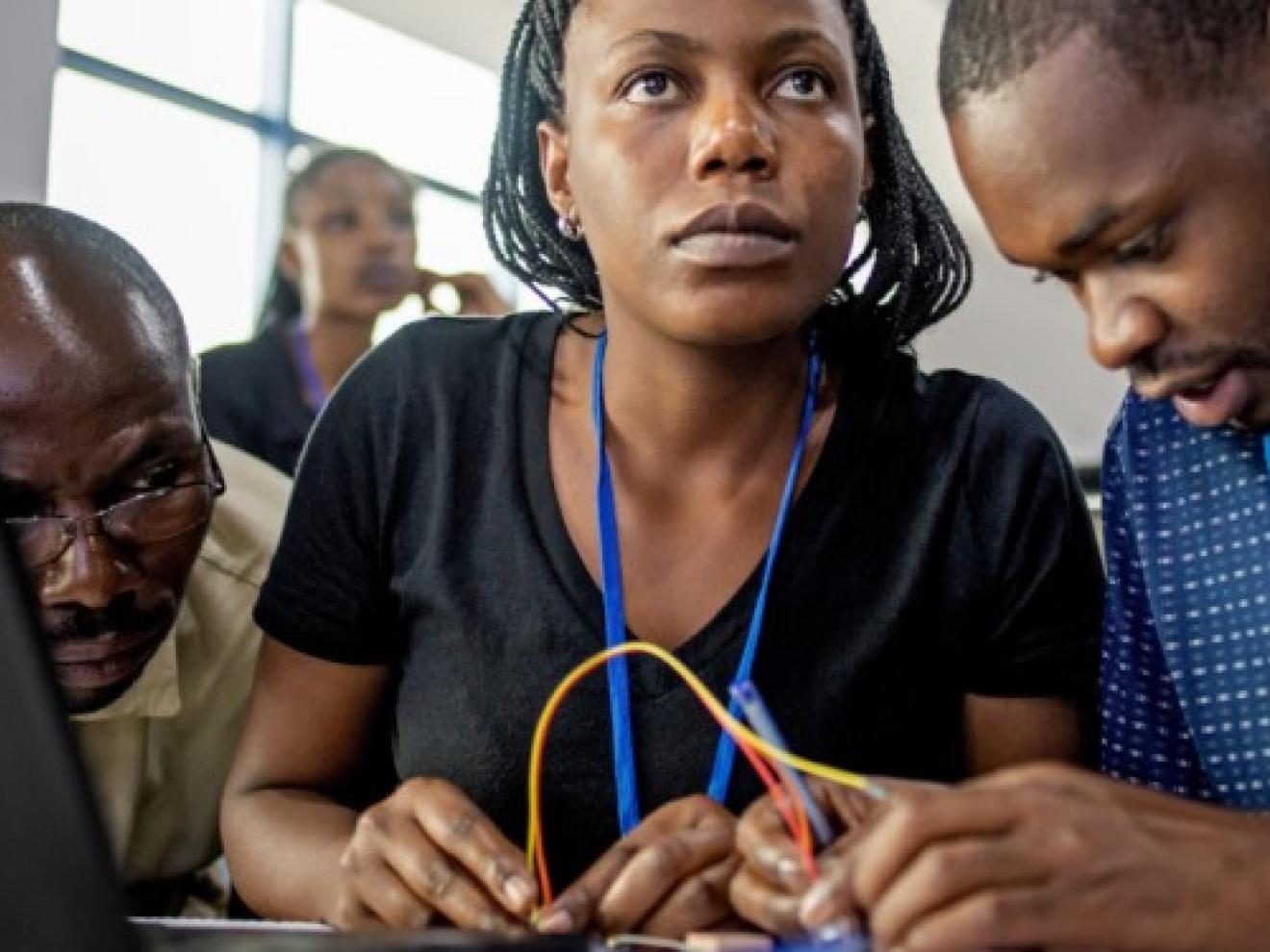 Drei IT-Entwickler*innen basteln an einem Computer.