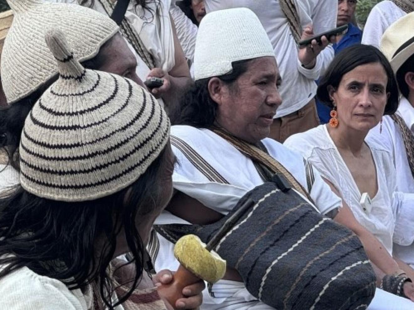 A group of representatives of indigenous groups in traditional dress sit in conversation with representatives of the COP16 Presidency in Tayrona, Colombia, in the run-up to COP16, with trees in the background.