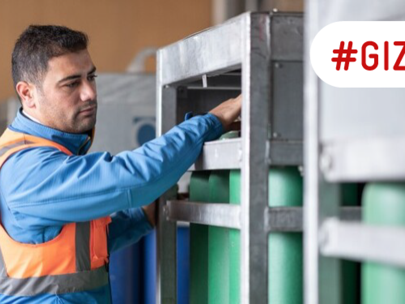 A man works with hydrogen cylinders that are stored in a steel container.