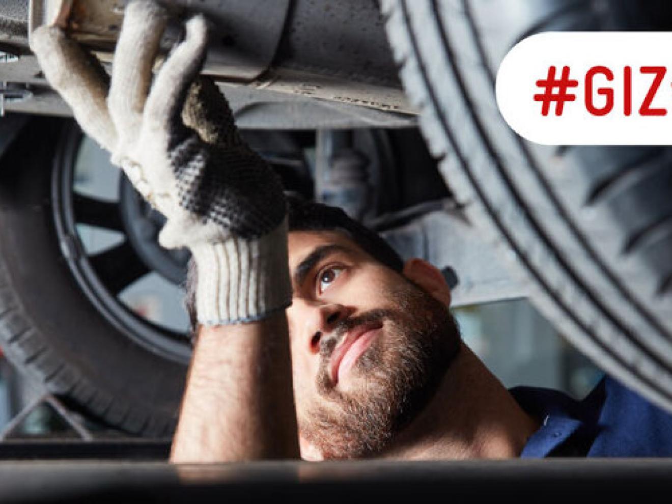 Ein Mechatroniker bei der Reparatur eines Auspuffs