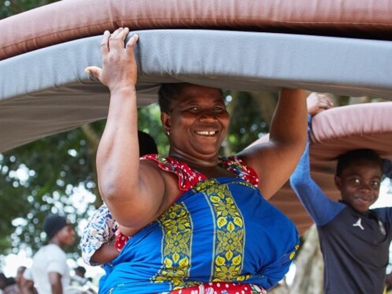 Eine Frau und ein Junge tragen Matratzen auf dem Kopf.