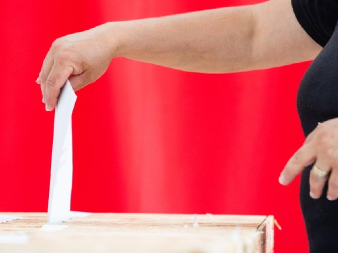 A woman deposits a ballot paper in a ballot box.