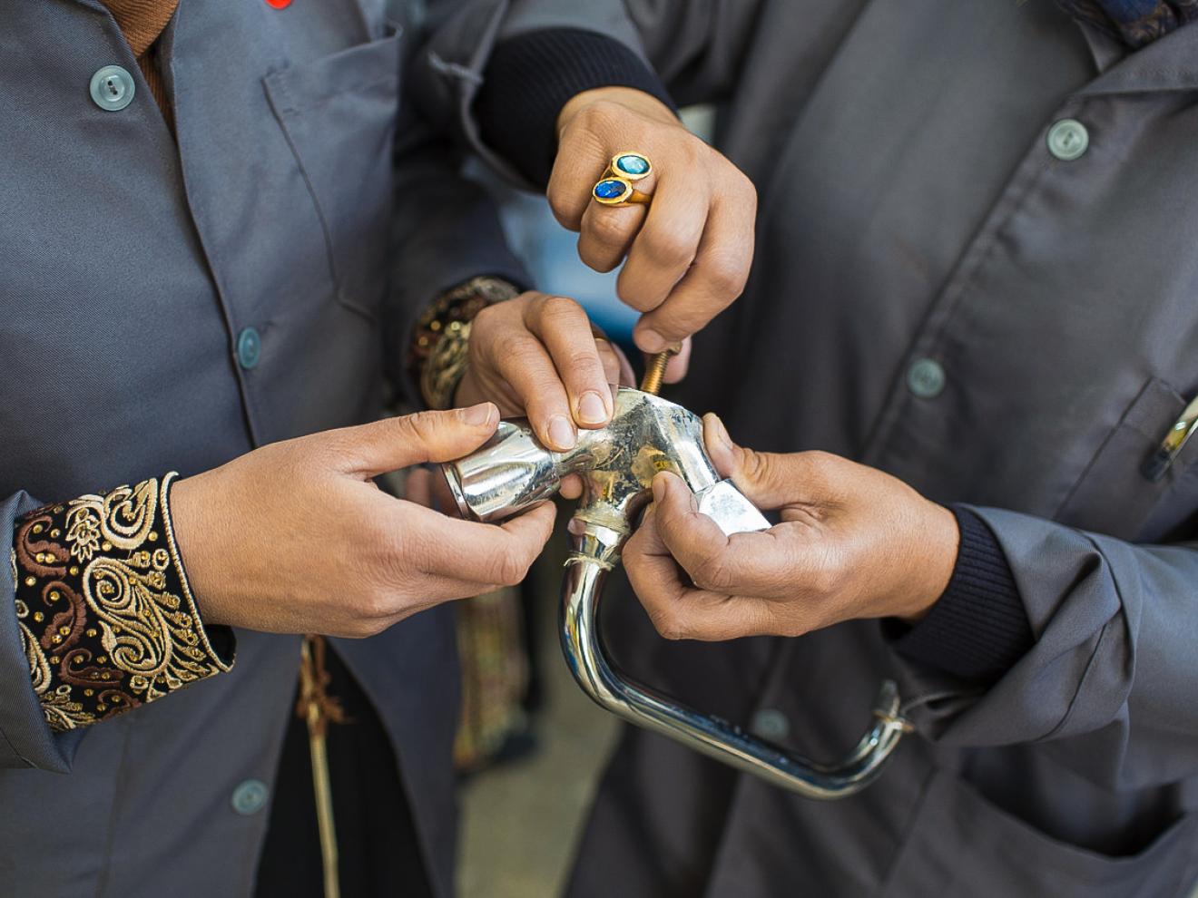 Zwei Personen schrauben an einem Wasserhahn