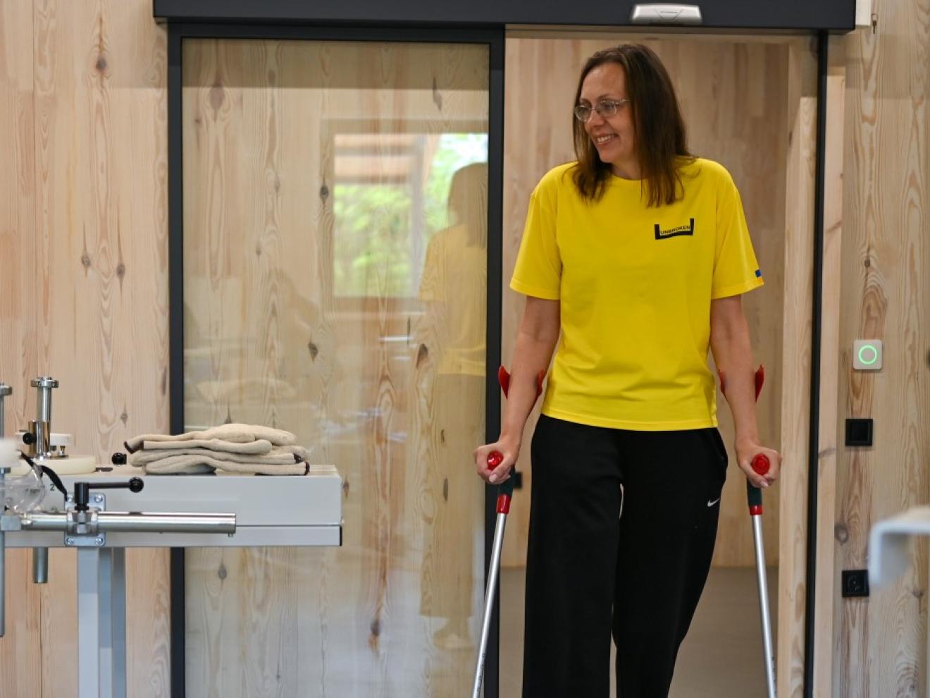 Eine Frau mit Gehhilfen schaut sich in der Werkstatt um