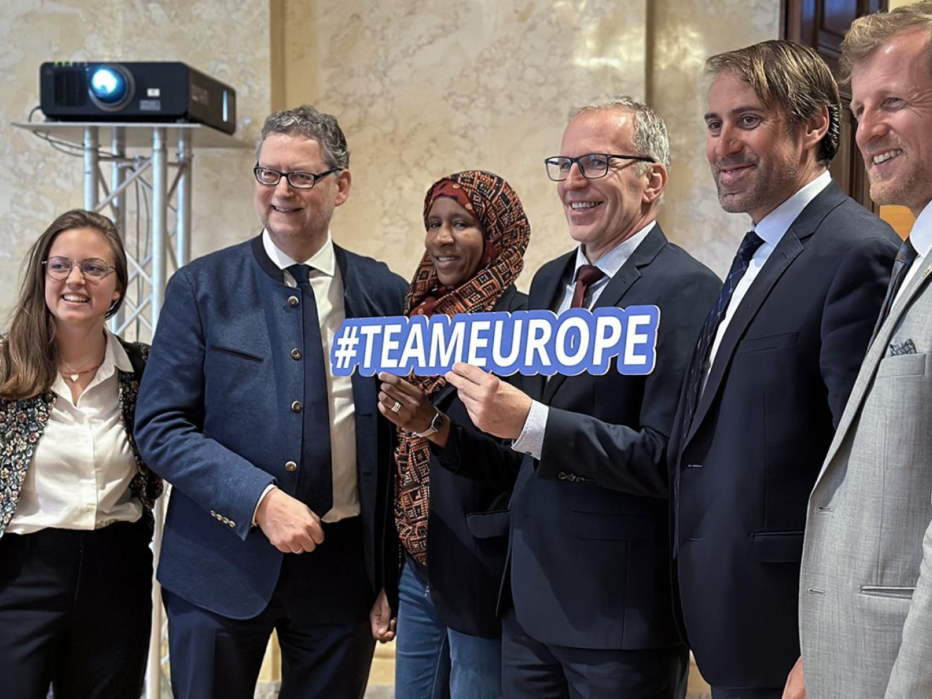 Six people posing together for a group photo, one person in the center holding a sign reading "#TEAMEUROPE".