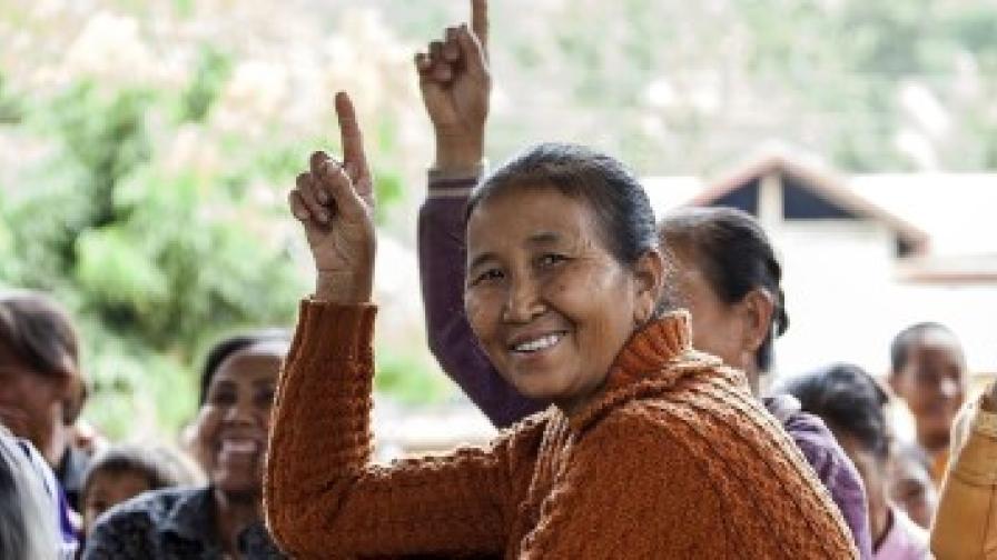 Eine Gruppe von Menschen. Zwei Frauen Heben die Hand.