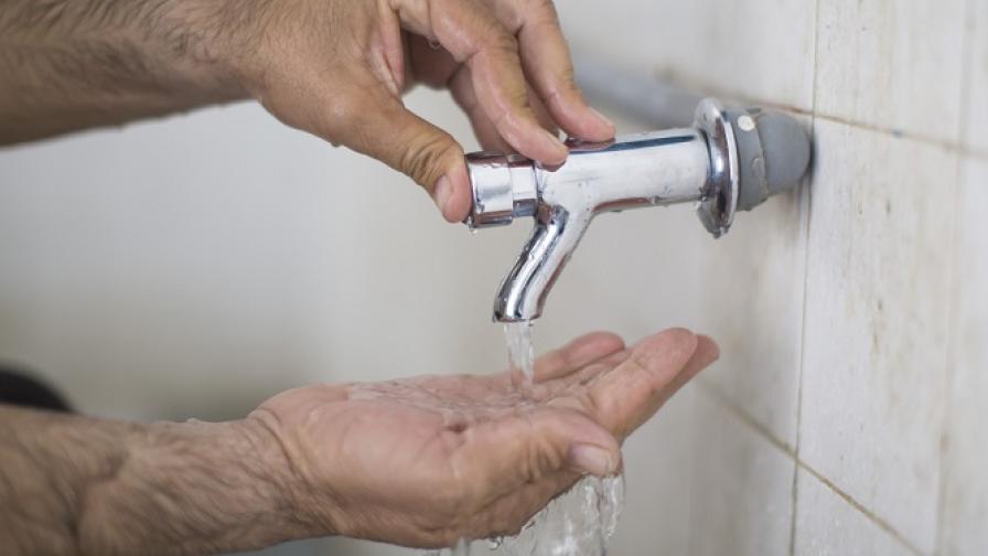 Close-up of a man’s hands with water running over them from a tap.