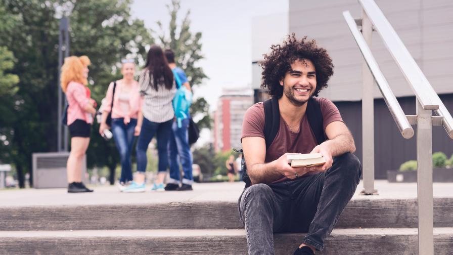 Studierender sitzt auf einer Treppe im öffentlichen Raum