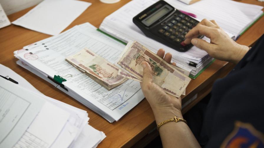 Eine Person zählt Geld auf einem Schreibtisch.