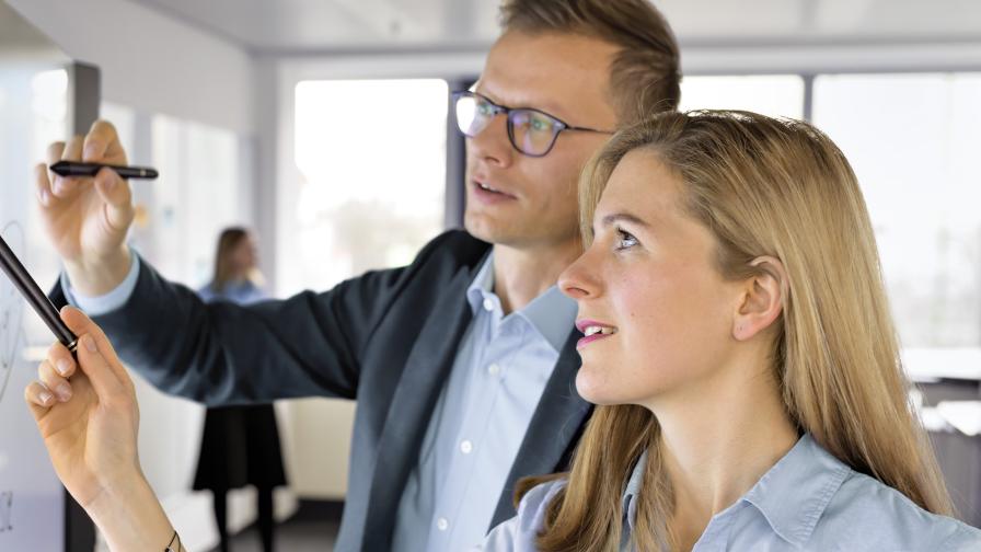 Digitalexpert:innen zeigen etwas an einem Whiteboard