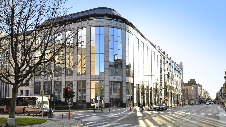 Außenansicht eines modernen Eckgebäudes mit vielen Fenstern an einer Straßenkreuzung.