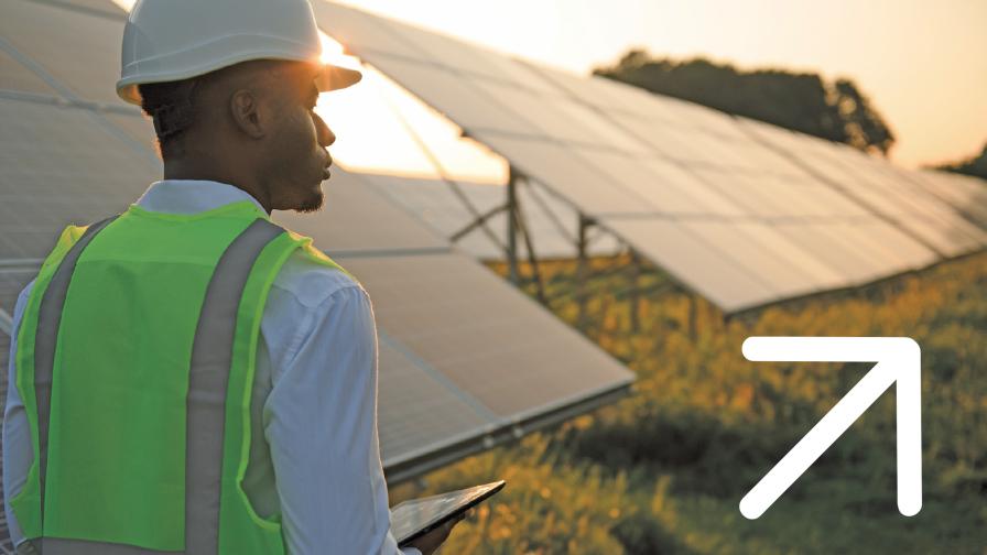 Mann in Schutzweste steht neben einer Photovoltaik-Anlage