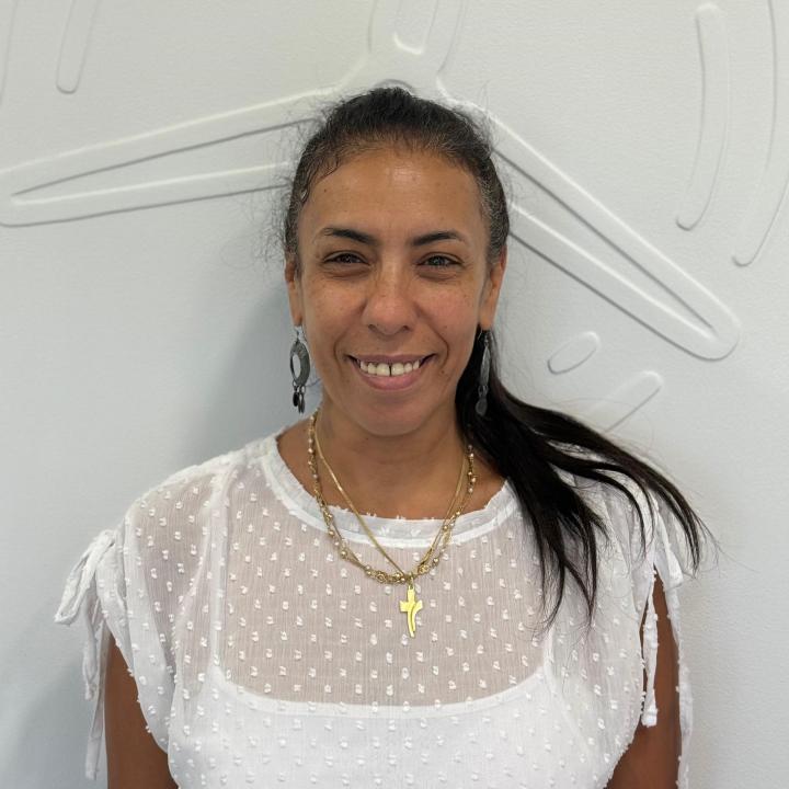 Hanna Reem steht vor einer weißen Wand und lächelt